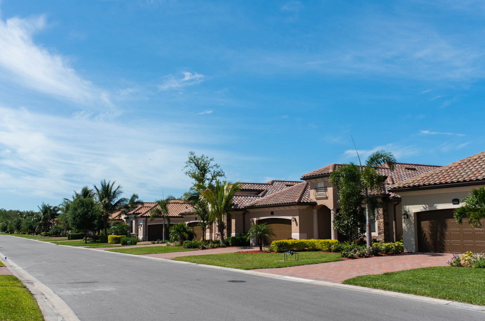 Residential street with modern homes, lush green lawns and blue sky in a suburban neighbourhood