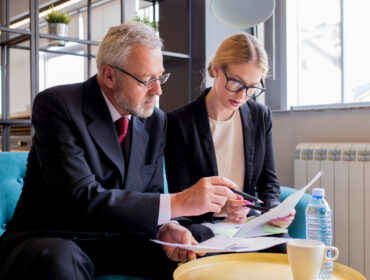 Two business professionals seated at a table, reviewing documents and discussing details