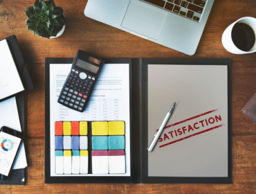The word "satisfaction" is written on a piece of paper resting on a wooden desk